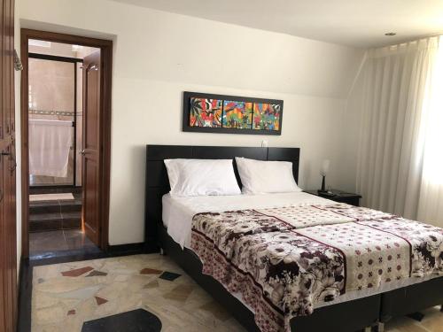 a bedroom with a bed and a painting on the wall at Hotel Campestre Cerritos Plaza in Pereira