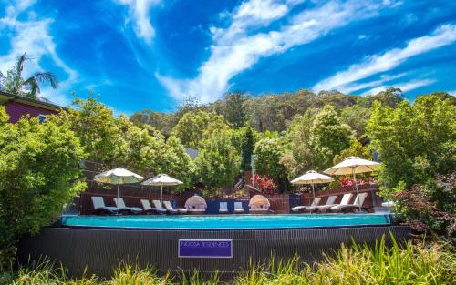 a swimming pool with chairs and umbrellas at Noosa Residences in Noosa Heads