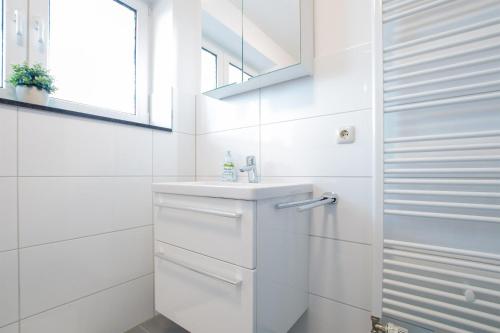 ein weißes Bad mit einem Waschbecken und einem Fenster in der Unterkunft Grüntal-Residenz Haus II App. 2 in Grömitz