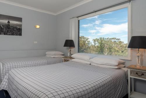 two beds in a room with a large window at Blue Mountains Highway Motel in Katoomba