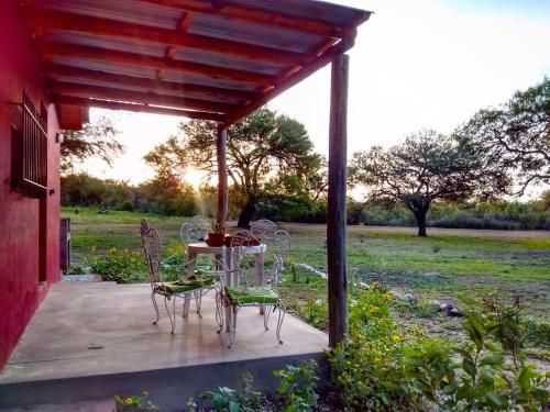 eine Terrasse mit einem Tisch und Stühlen auf einer Veranda in der Unterkunft Cabañas Los Algarrobos in San Marcos Sierras