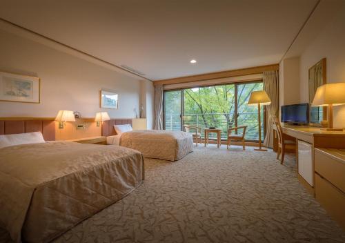 a hotel room with two beds and a desk and a television at Iizaka Onsen Surikamitei Ohtori in Fukushima