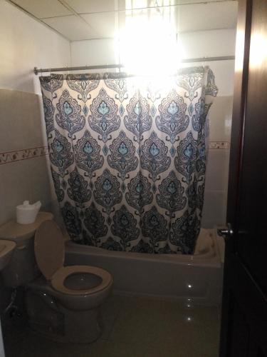 a bathroom with a toilet and a shower curtain at SANTIAGO CITY in Santiago de los Caballeros