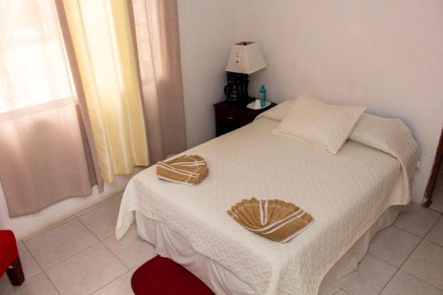 a bedroom with a white bed with two hats on it at Hostería "El Paraíso" in Montañita