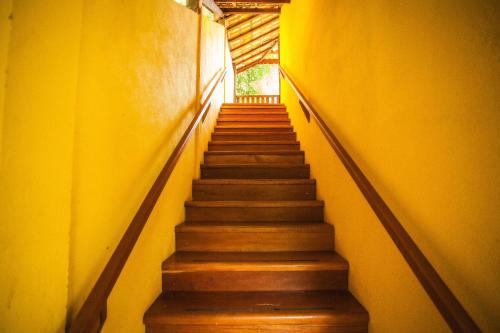 a stairway leading up to a room with yellow walls at Pousada Refugio dos Palmares in São Bento do Sapucaí