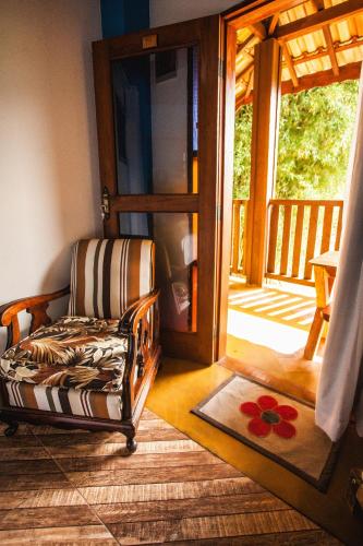 a room with a chair in front of a door at Pousada Refugio dos Palmares in São Bento do Sapucaí