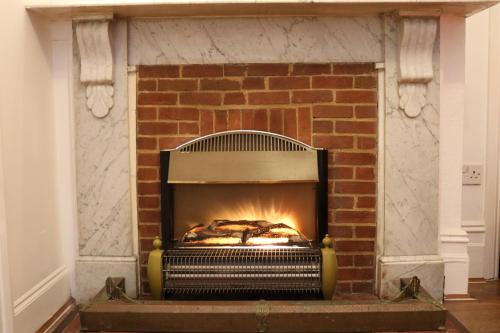 a brick fireplace with a fire in it at Anand Lodge in Royal Tunbridge Wells