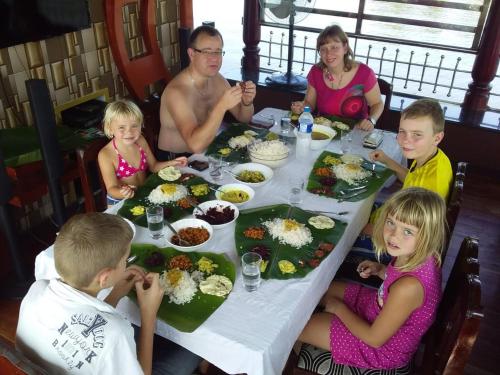 a group of people sitting around a table with food at Vaishnav Tours in Alleppey