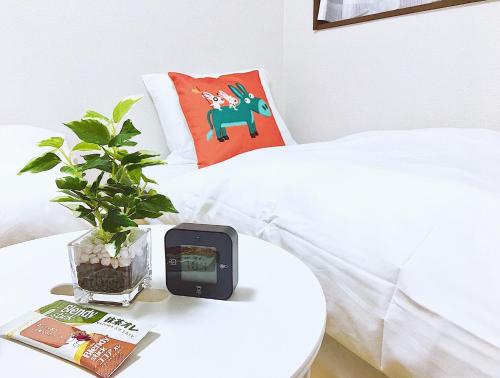 a white bed with a table with a clock on it at Alo BnB 3 - Near KOMAGOME, IKEBUKURO, SHINJUKU, UENO - MAX 16 PAX in Tokyo