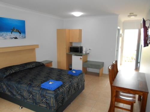 a bedroom with a bed and a table and a kitchen at TI Motel Torres Strait in Thursday Island