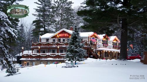 a large building with a christmas sign on it in the snow at Edgewater Inn & Cottages in Eagle River