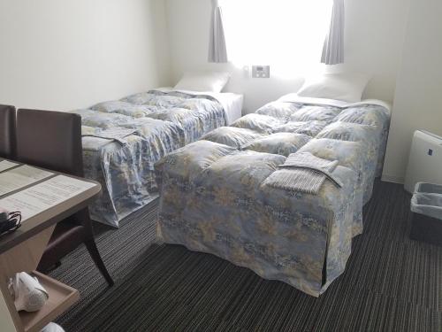 una camera d'albergo con 2 letti e una scrivania di Murayama Nishiguchi Hotel a Murayama