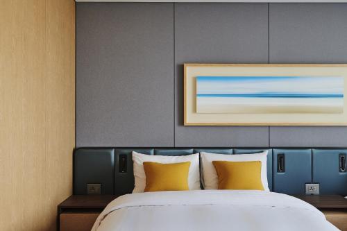a bedroom with a large bed with yellow pillows at Hotel Hyundai by Lahan Ulsan in Ulsan