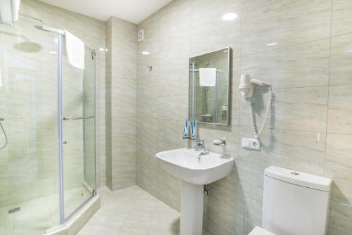 uma casa de banho com um lavatório, um chuveiro e um WC. em Royal Petrol Hotel em Taldykorgan
