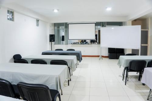 a conference room with tables and chairs and a projection screen at Hotel Fatima Inn in Tarapoto