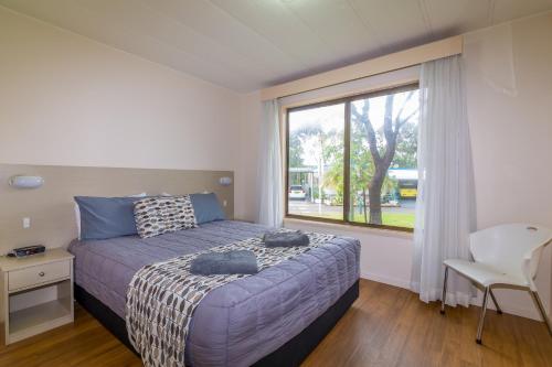 een slaapkamer met een bed en een groot raam bij Wollongong Surf Leisure Resort in Wollongong