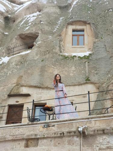 a woman standing on a balcony in front of a building at Elite Cave Suites in Goreme