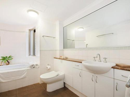 La salle de bains blanche est pourvue d'un lavabo et de toilettes. dans l'établissement Byron Beaches Location, à Byron Bay