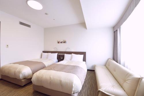 two beds in a hotel room with a couch at Hotel Port Plaza Chiba in Chiba