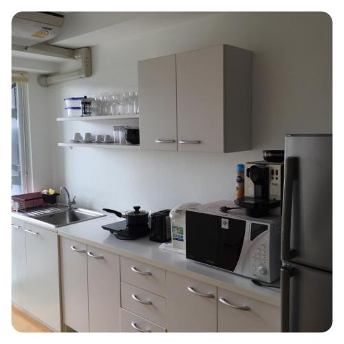 a kitchen with white cabinets and a black refrigerator at Apartment in Ranghill Residence Phuket by month in Phuket