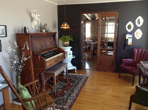 an old piano in a living room with a table at Hôtel-Motel Vagues Vertes in Perce