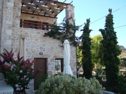 a building with a white umbrella outside of it at Lithos Traditional Guest Houses in Xerokampos