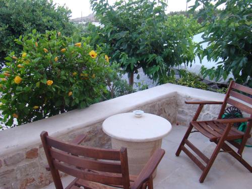 two chairs and a table on a patio with trees at Lithos Traditional Guest Houses in Xerokampos