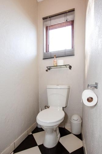 a bathroom with a white toilet and a window at Windmills Rest in Pretoria