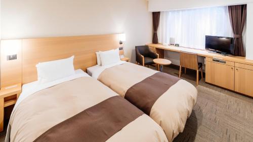 a hotel room with two beds and a television at Hachinohe Park Hotel in Hachinohe