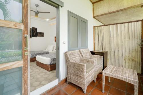 a room with a balcony with a chair and a bed at Casa Asia in Uluwatu