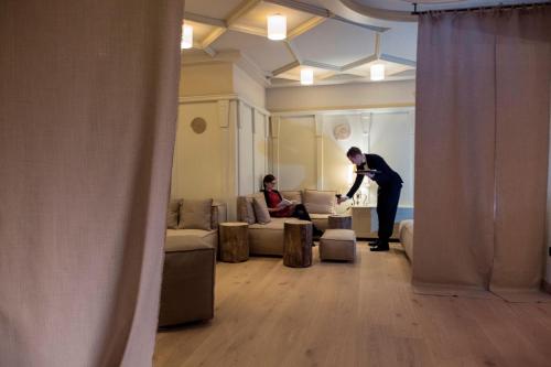 a man standing in a living room taking a picture of a woman at La Roccia Wellness Hotel in Cavalese