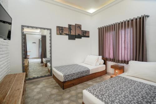 a hotel room with two beds and a mirror at Casa Asia in Uluwatu
