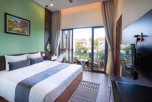 a bedroom with a large bed and a balcony at Le Printemps d' An Bang in Hoi An