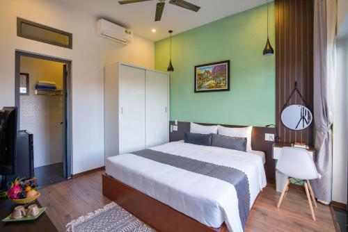 a bedroom with a large white bed and a green wall at Le Printemps d' An Bang in Hoi An