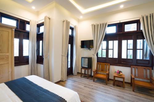 a bedroom with a bed and a tv and windows at Le Printemps d' An Bang in Hoi An