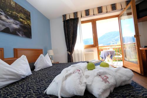 a bedroom with a bed with a white blanket at La Roccia Wellness Hotel in Cavalese