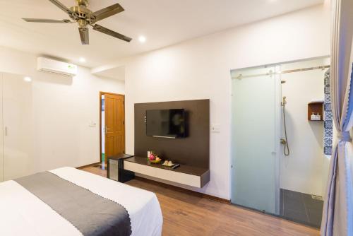 een slaapkamer met een bed en een tv aan de muur bij Le Printemps d' An Bang in Hội An