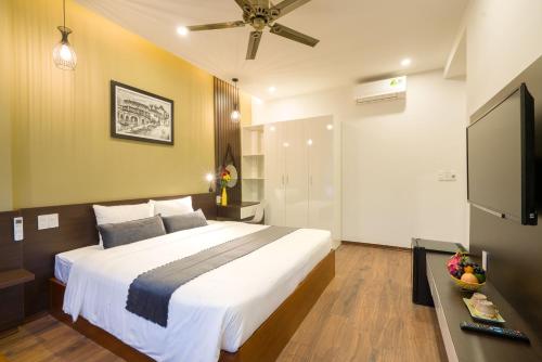 a bedroom with a large bed and a flat screen tv at Le Printemps d' An Bang in Hoi An