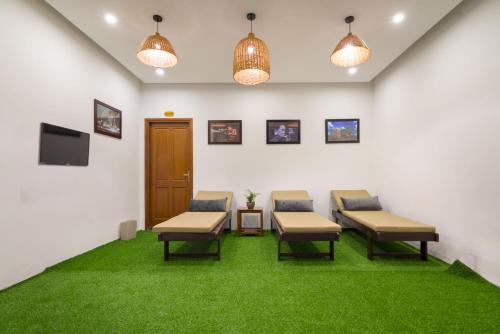 a waiting room with chairs and a tv and grass at Le Printemps d' An Bang in Hoi An