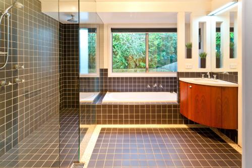 La salle de bains est pourvue d'une baignoire, d'un lavabo et d'une fenêtre. dans l'établissement Pure Indulgence, à Merimbula