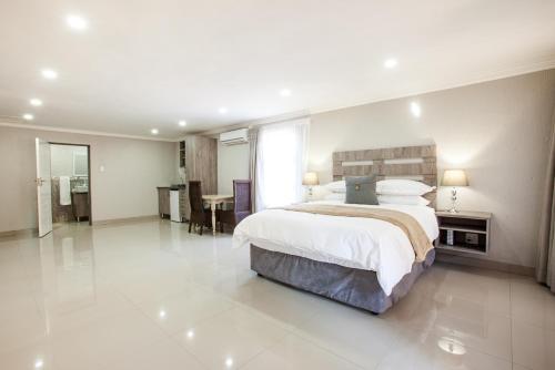 a large bedroom with a large bed and a table at Windmills Rest in Pretoria