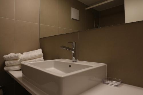 La salle de bains est pourvue d'un lavabo, d'un miroir et de serviettes. dans l'établissement Bolero 4.5 Dachzimmerwohnung, à Zermatt