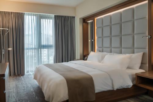 a bedroom with a large bed and a large window at Landmark Amman Hotel & Conference Center in Amman