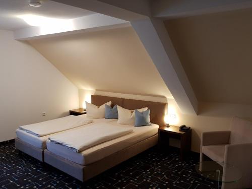 a bedroom with a large bed and a chair at Hotel Königer in Pliening