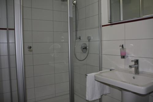 een witte badkamer met een douche en een wastafel bij Wirtshaus am Markt in Markt Nordheim