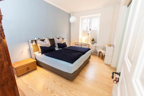 Schlafzimmer mit einem Bett mit blauer Bettwäsche und Holzböden in der Unterkunft quartier kiel plus in Kiel