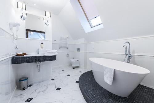 a white bathroom with a tub and a toilet at Hotel St. Bruno in Giżycko