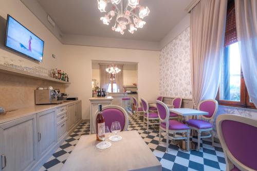 una cucina con sedie viola e un tavolo con una bottiglia di vino di Villa Elda Boutique Hotel a Siena