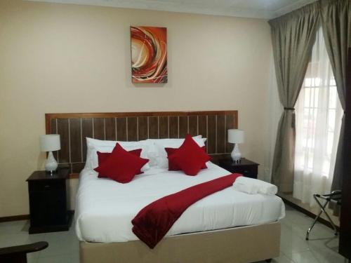 a bedroom with a large bed with red pillows at Vido Lodge and Conference Centre in Polokwane