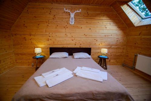 a bed in a wooden room with two towels on it at Shale Verba in Kvasy